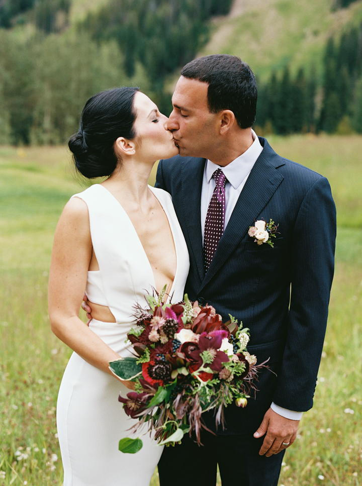 newlyweds kissing with burgundy bouquet