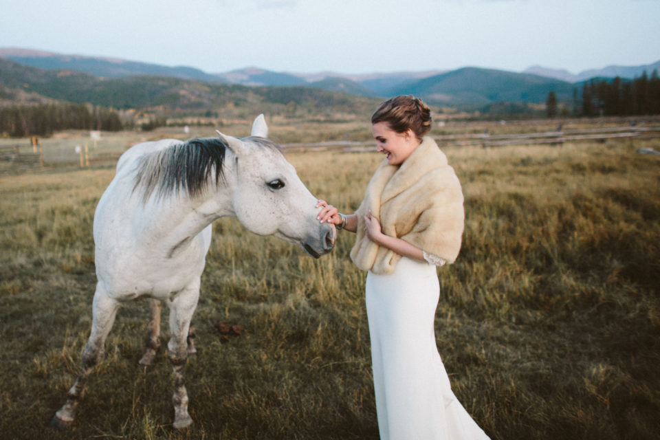 bride in fur petting white horse