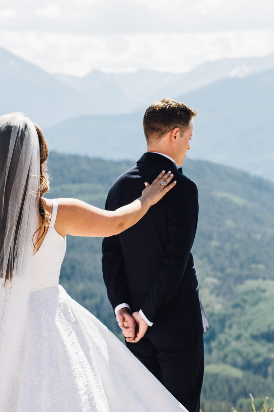 bride tapping groom for first look on vail mountain deck
